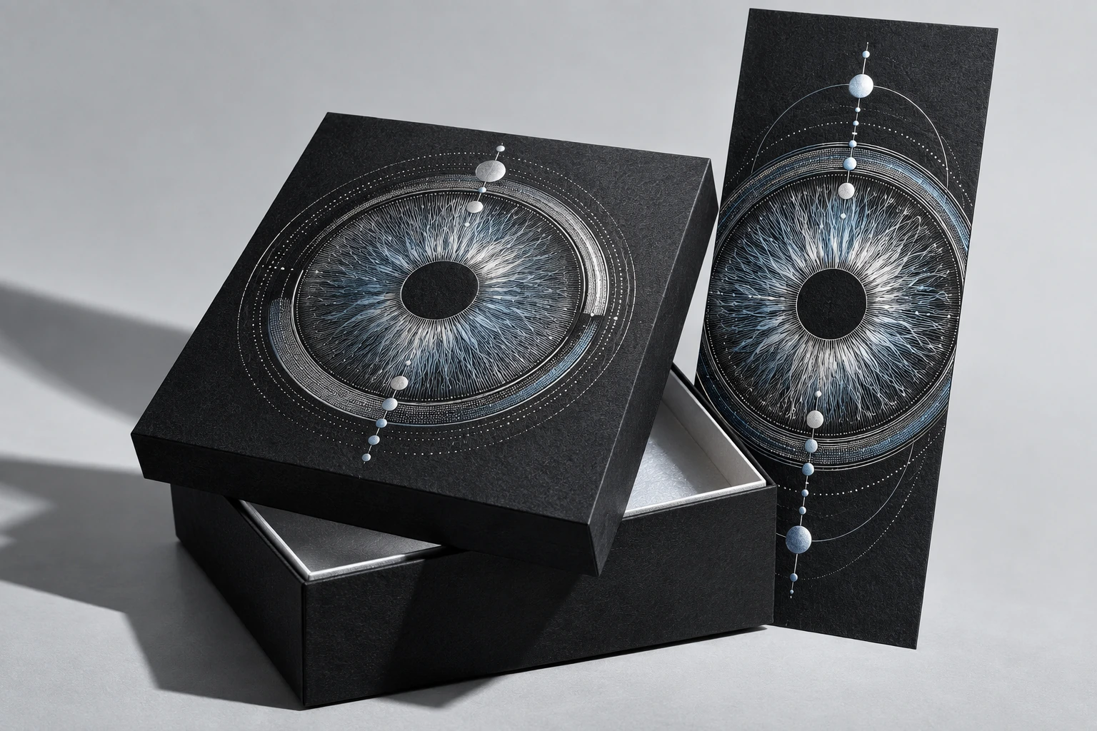 A black presentation box and invitation with silver orbital patterns
